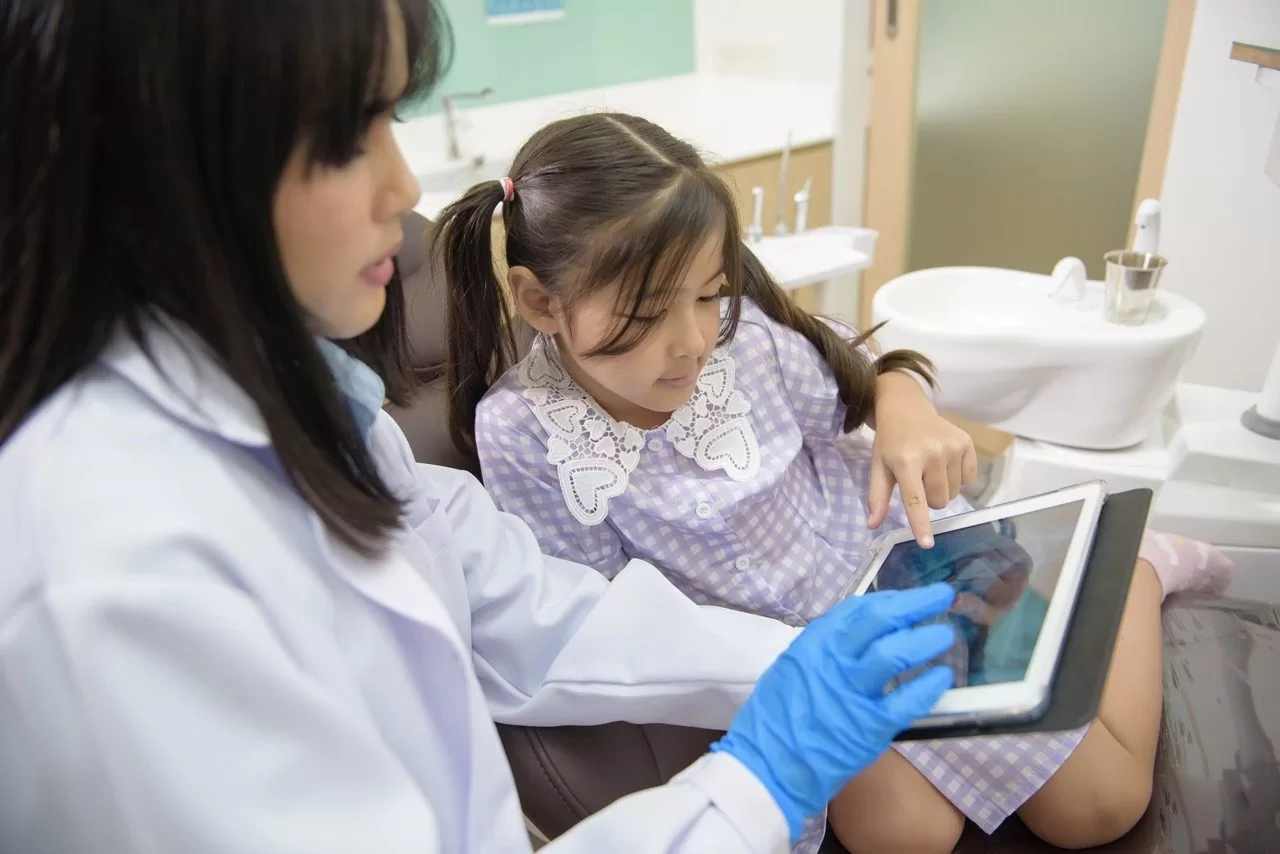 Dentist showing a child dental images on a tablet during a pediatric sedation dentistry consultation
