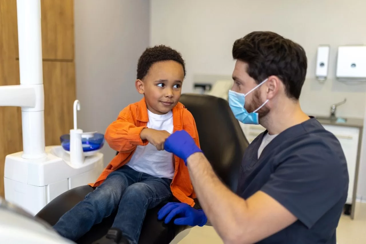 Dentist reassuring a toddler in a dental chair before treatment, highlighting safe dental sedation options for young children.