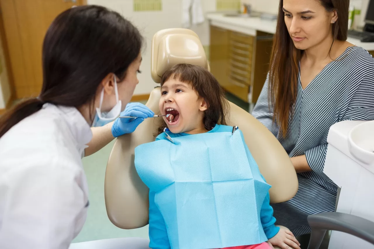 Pediatric dentist examining a child with parent present