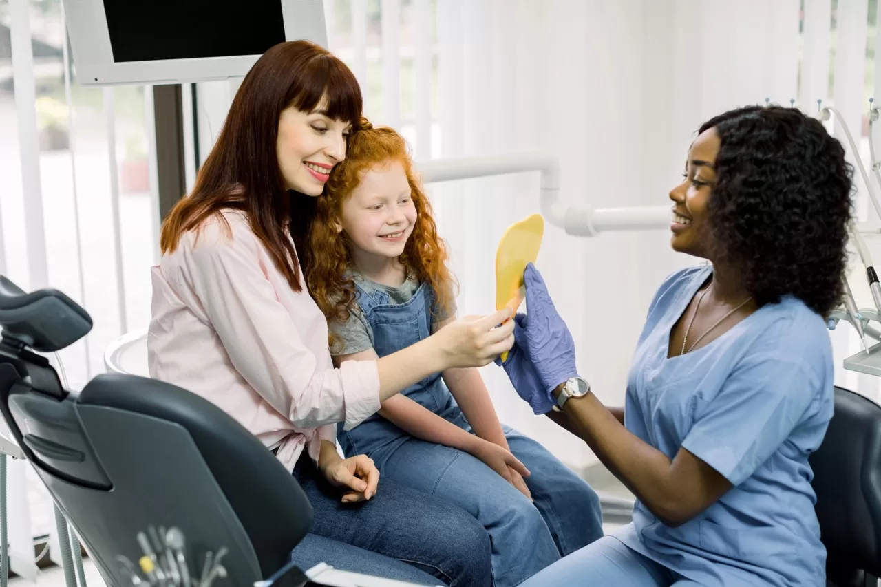 Parent and child smiling during a pediatric dental appointment with a dentist