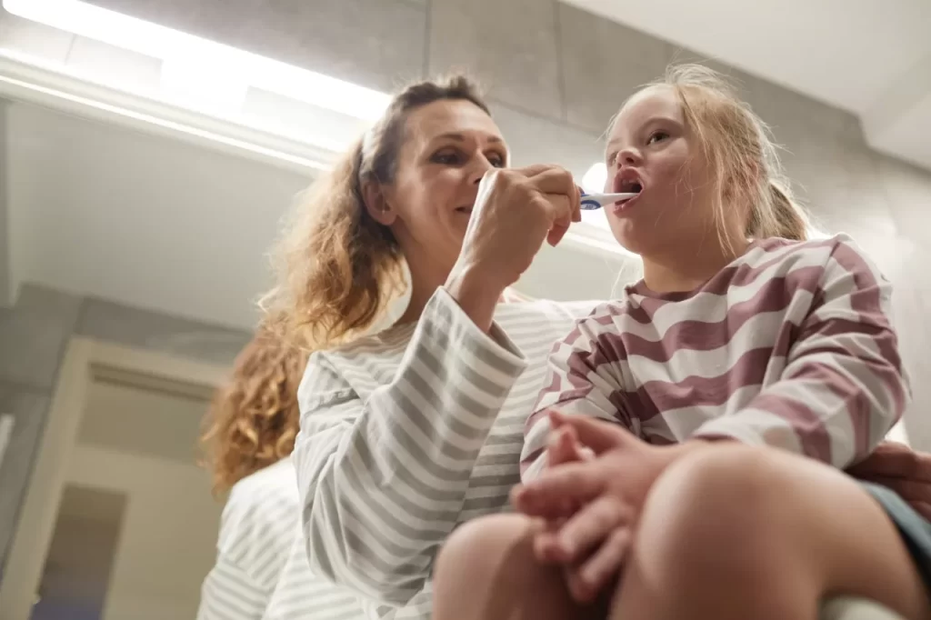 Parent helping a child brush teeth