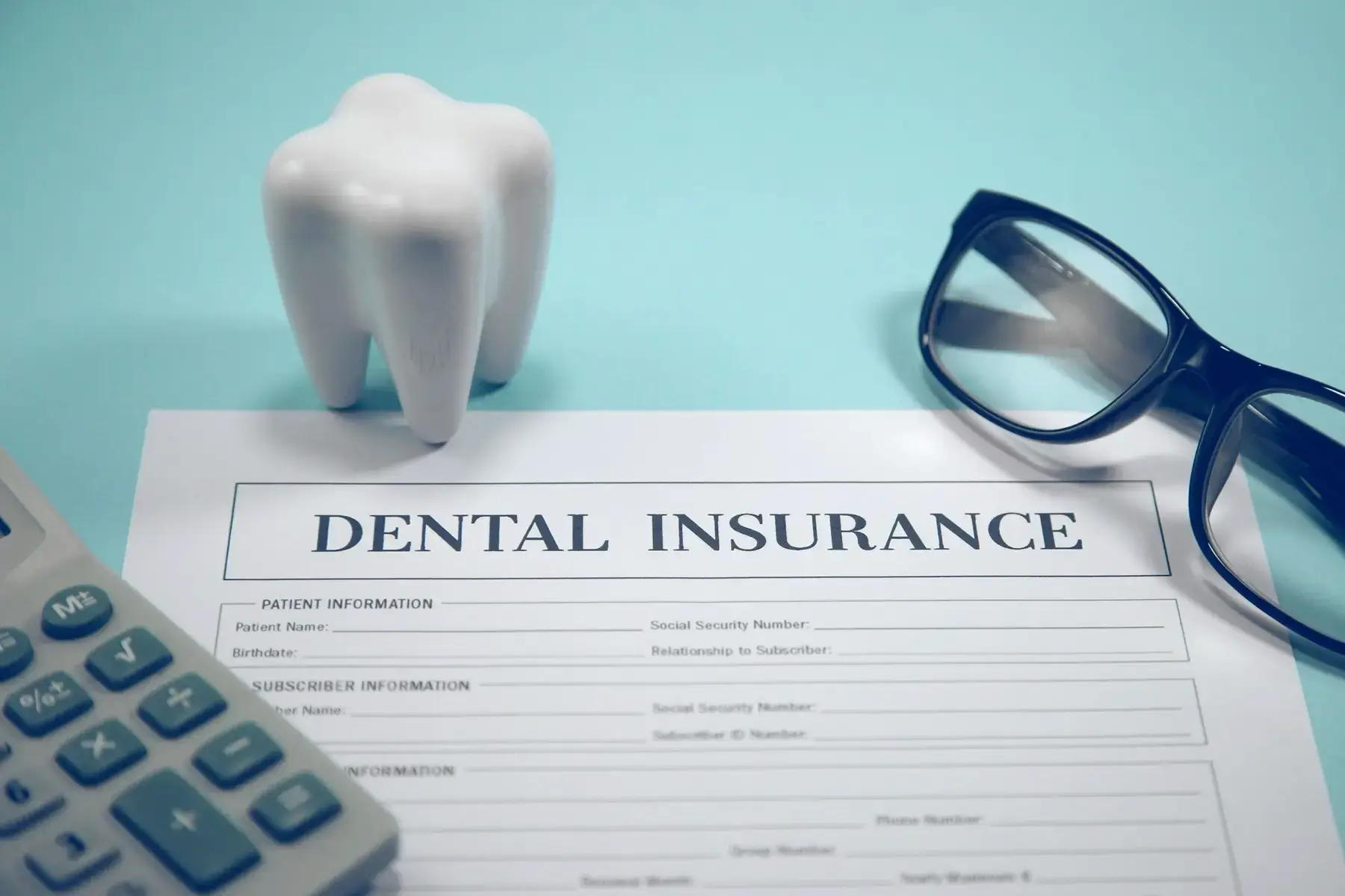 Dental insurance form with tooth model, glasses, and calculator on a blue background
