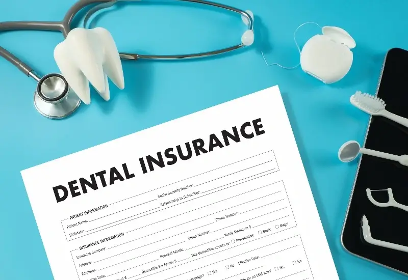 Dental insurance form with tooth model, stethoscope, toothbrush, floss, and phone